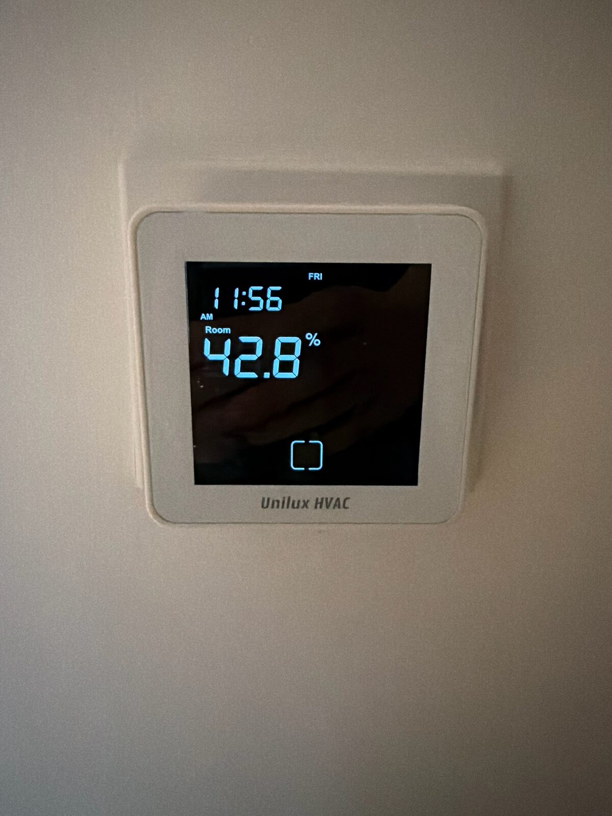 A wall-mounted Unilux fan-coil thermostat.